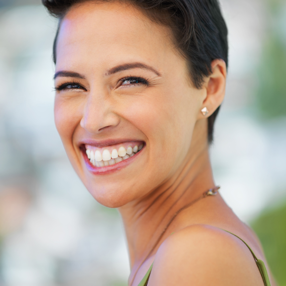Patient holding up a dental shade guide guide to her teeth